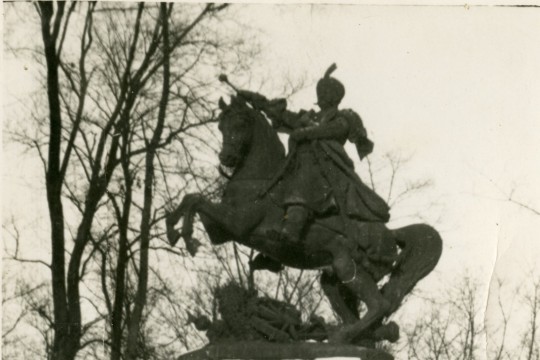 Zima. Dwóch mężczyzn stoi pod pomnikiem konnym Jana III Sobieskiego.
