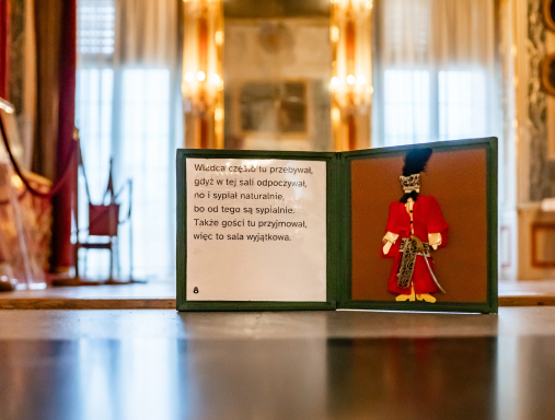 Podłoga w Bibliotece Króla: trójkolorowa, iluzjonistyczna mozaika. Na niej otwarty przewodnik sensoryczny.